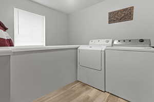 Laundry area featuring light wood-style floors and independent washer and dryer