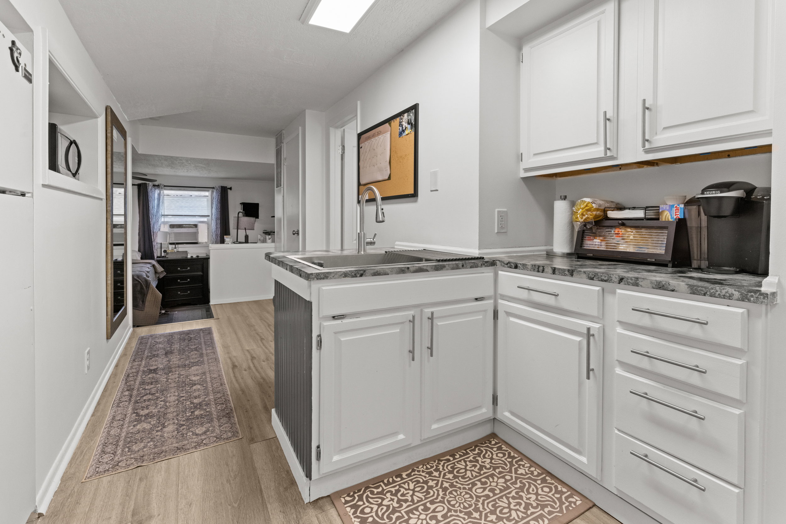 Kitchen featuring white cabinetry, open floor plan, a peninsula, light wood-style flooring, and cooling unit