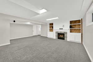 Unfurnished living room with built in features, carpet, and a tile fireplace