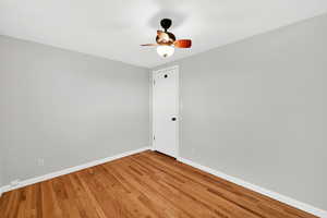 Unfurnished room with wood finished floors and a ceiling fan