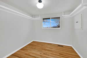 Empty room featuring light wood finished floors, electric panel, and a textured ceiling