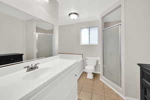 Bathroom featuring a shower stall, vanity, and light tile patterned flooring