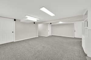 Finished below grade area featuring baseboards and light carpet