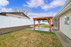 Fenced backyard featuring a patio and a gazebo