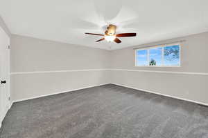 Unfurnished room featuring dark colored carpet and ceiling fan