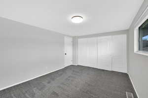 Unfurnished bedroom featuring dark carpet and a closet