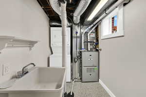 Utility room featuring stacked washer and clothes dryer and heating unit