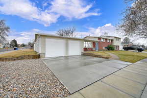 Tri-level home with a chimney, driveway, a front lawn, and brick siding