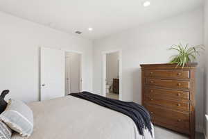 Bedroom featuring connected bathroom, recessed lighting, and light carpet