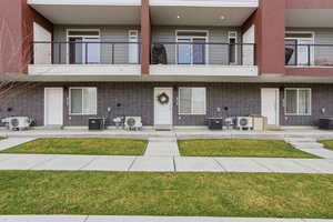 View of front facade with a balcony, a front yard, and brick siding