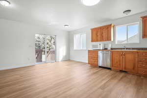 Kitchen with stainless steel dishwasher, wood finish cabinetry, white microwave, healthy amount of natural light, and a textured ceiling
