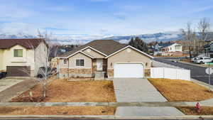 View of front of house featuring driveway, a residential view, stucco siding, an attached garage, and stone siding