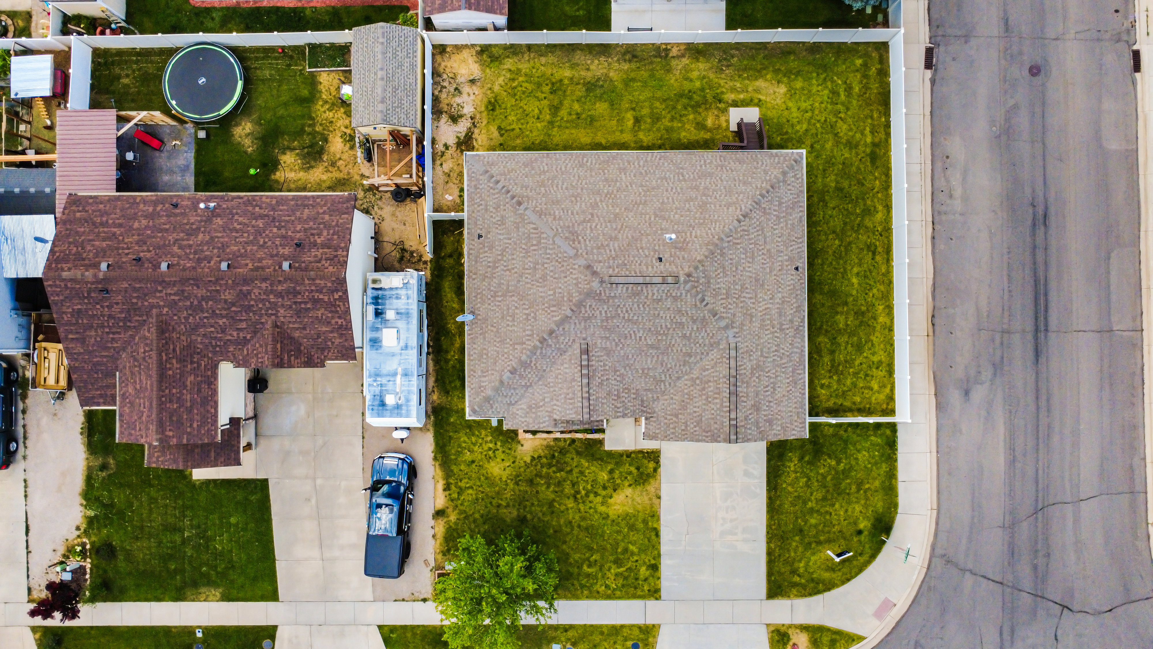 Aerial perspective showcasing a property with a brown shingle roof and a concrete driveway