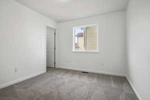 Carpeted empty room featuring baseboards