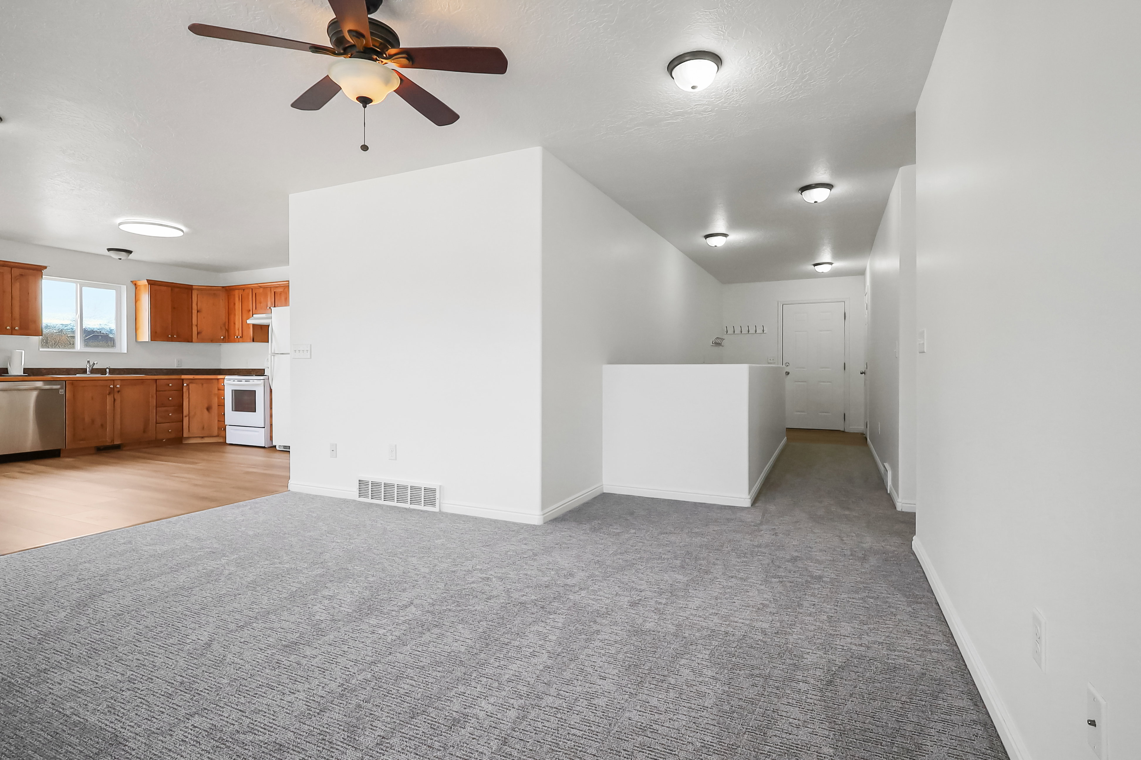 Unfurnished living room featuring ceiling fan and light carpet