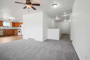 Unfurnished living room featuring ceiling fan and light carpet