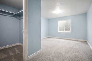 Unfurnished bedroom featuring a textured ceiling and carpet