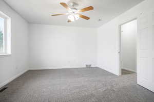 Empty room with a ceiling fan and carpet flooring