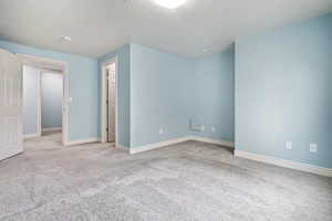 Carpeted spare room with a textured ceiling and baseboards