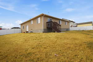 Back of property with a fenced backyard, stucco siding, a gate, and a wooden deck