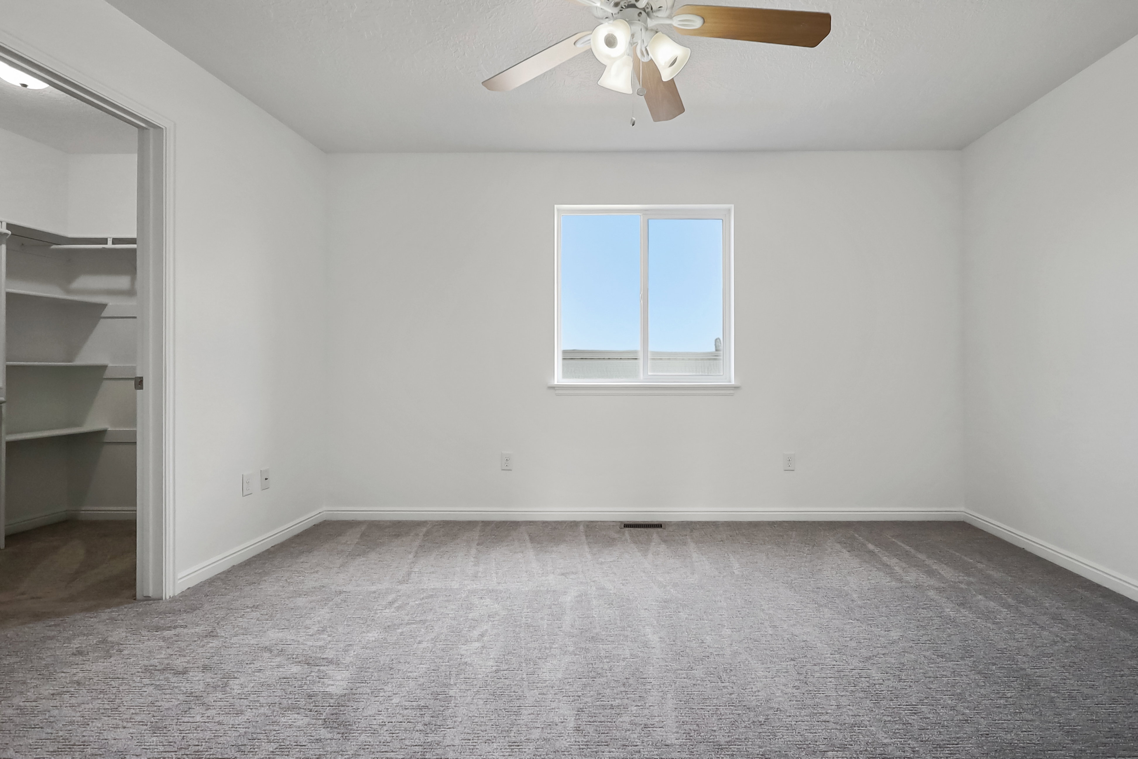 Unfurnished bedroom with a walk in closet, light carpet, and a ceiling fan