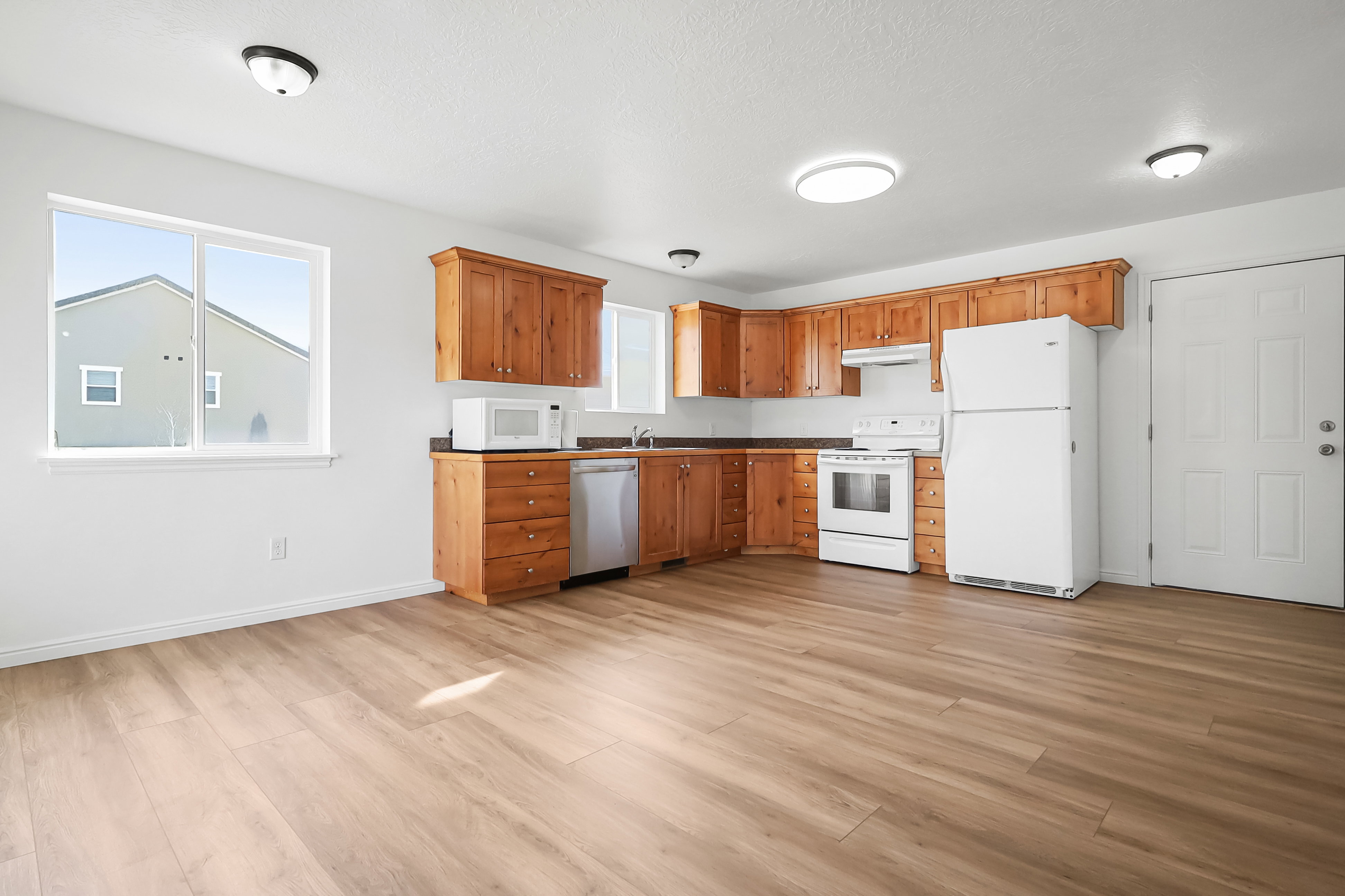 Kitchen with white appliances, wood finish cabinets, and light wood finished floors