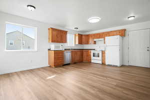 Kitchen with white appliances, wood finish cabinets, and light wood finished floors