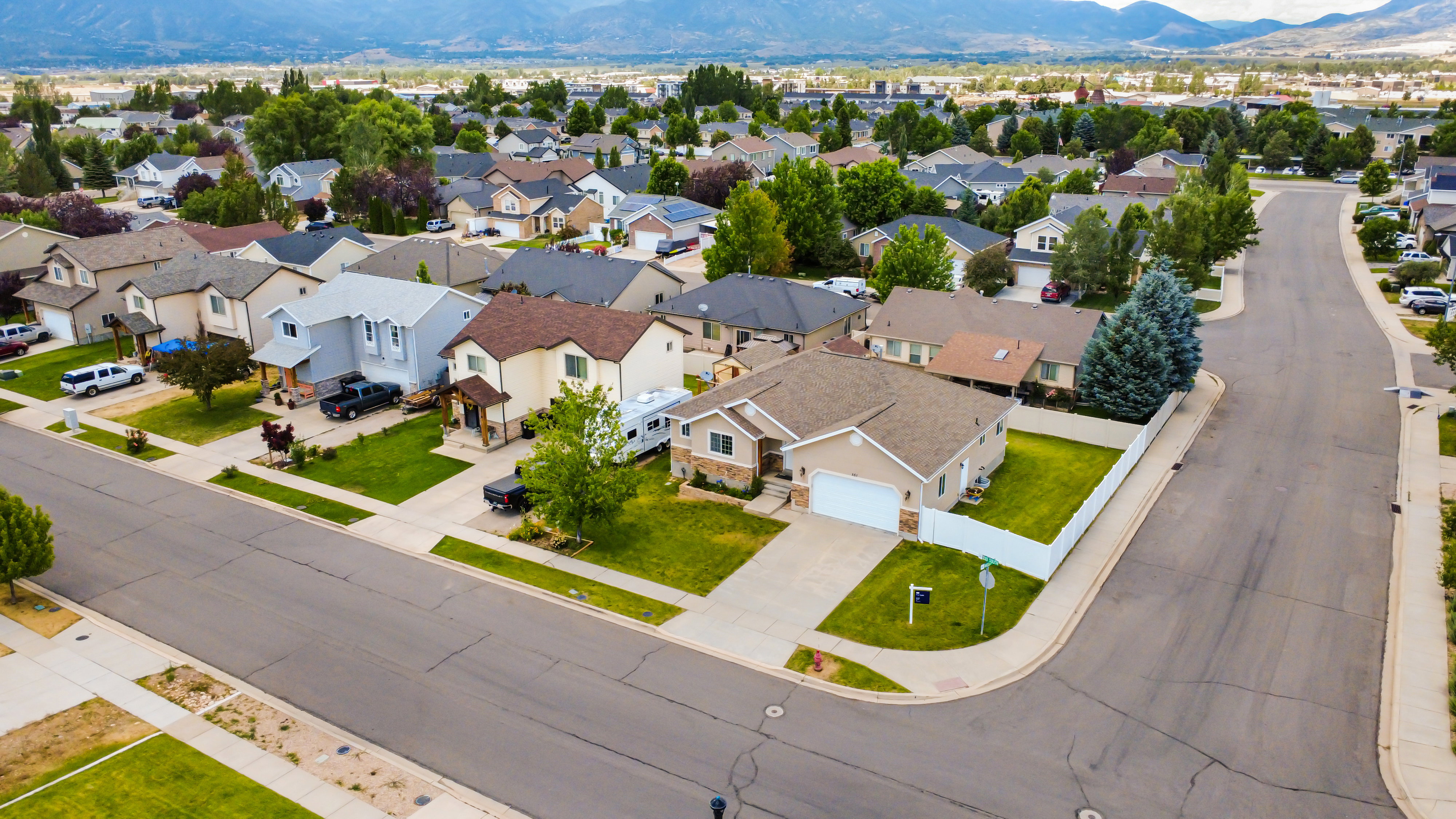 Corner lot property with a two-car garage, manicured lawn, and a white privacy fence