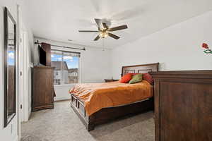 Primary bedroom with light carpet, and a ceiling fan