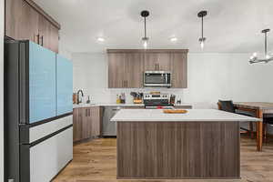 Kitchen with stainless steel appliances, a kitchen island, decorative backsplash, and wood finish cabinetry