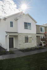 View of front of property with stone siding, board and batten siding, and a front lawn