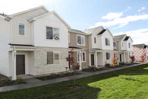 View of front of home with stone siding, a front yard, and a residential view