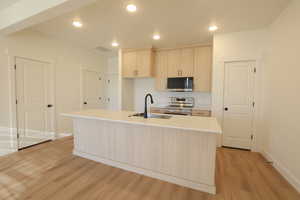 Kitchen featuring light wood finish cabinets, stainless steel appliances, a kitchen island with sink, light wood-style floors, and recessed lighting