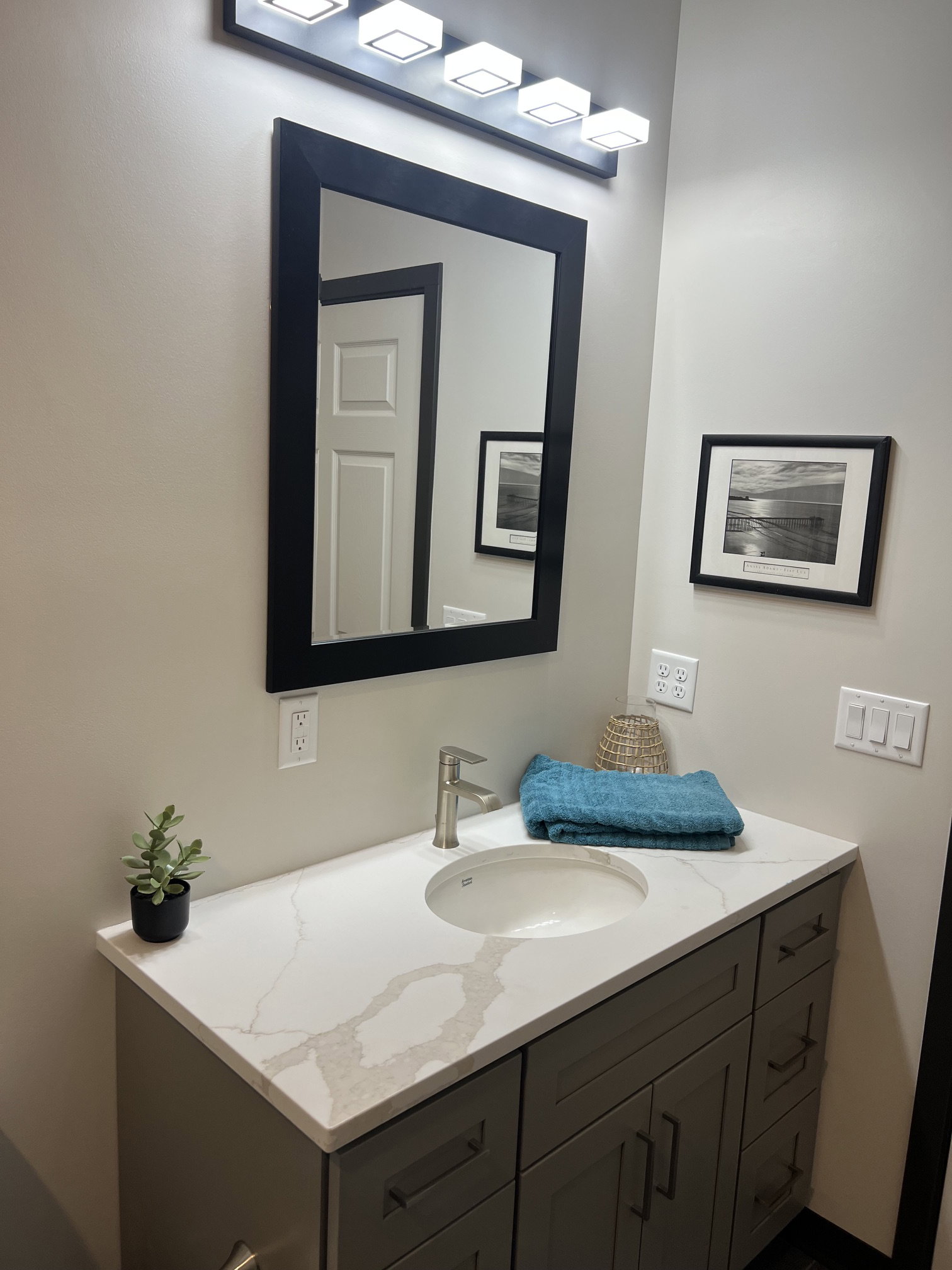 Modern vanity featuring a light-toned countertop with veining, an undermount sink, and a brushed nickel faucet