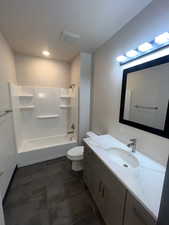Bathroom featuring vanity, shower / bathtub combination, and dark tile patterned floors