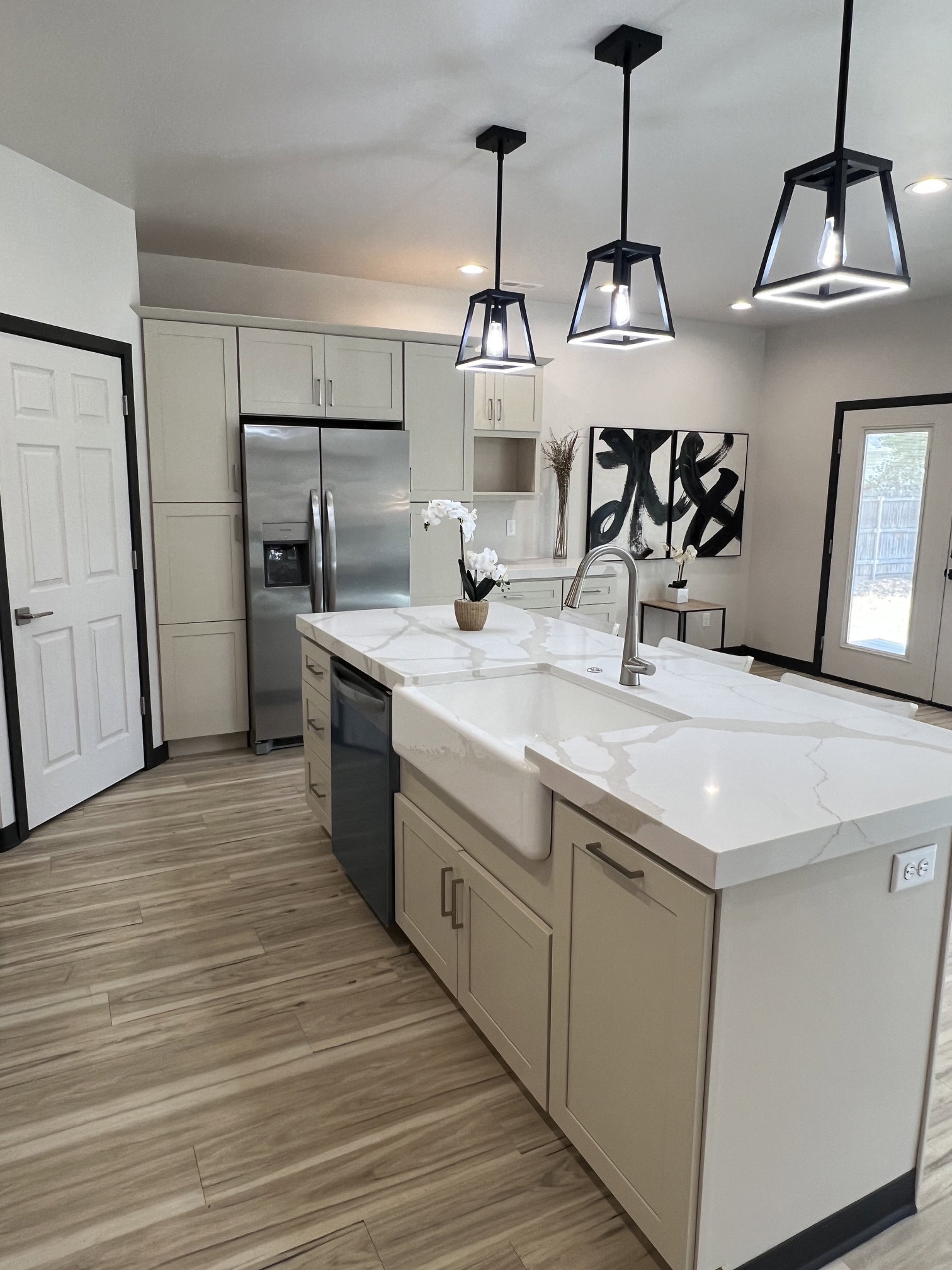 Modern kitchen featuring an expansive center island with a farmhouse sink and light-toned countertops