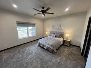 Carpeted room featuring a ceiling fan, recessed lighting, and a large window with a roller shade