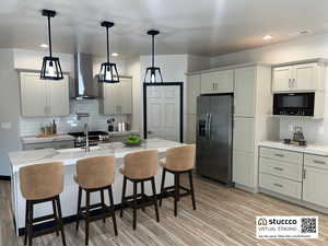 Kitchen with stainless steel appliances, decorative light fixtures, a breakfast bar area, and light wood-style flooring