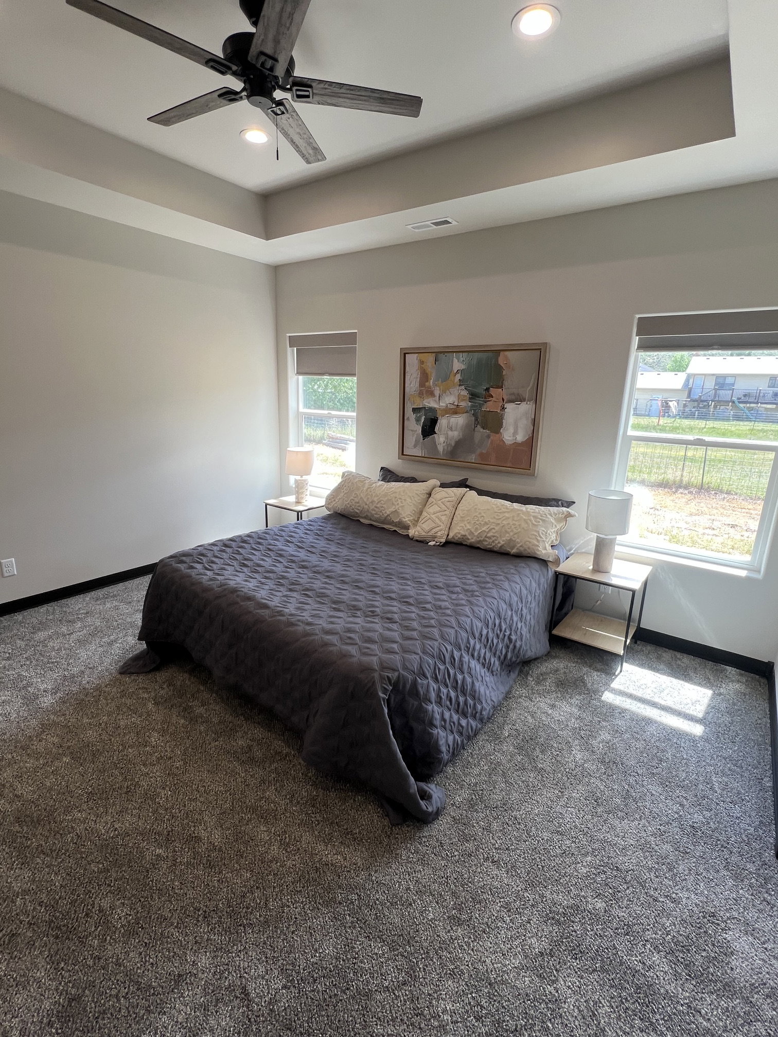 Spacious room featuring a tray ceiling with recessed lighting and a ceiling fan