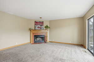 Unfurnished living room with light colored carpet and a tile fireplace