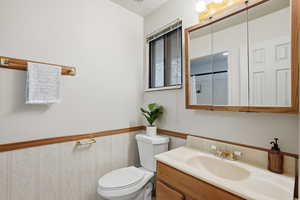 Full bathroom featuring vanity and a wainscoted wall