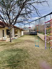 Fenced yard with a playground, a trampoline, and a patio area