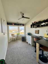 Home office with lofted ceiling, light carpet, and a ceiling fan