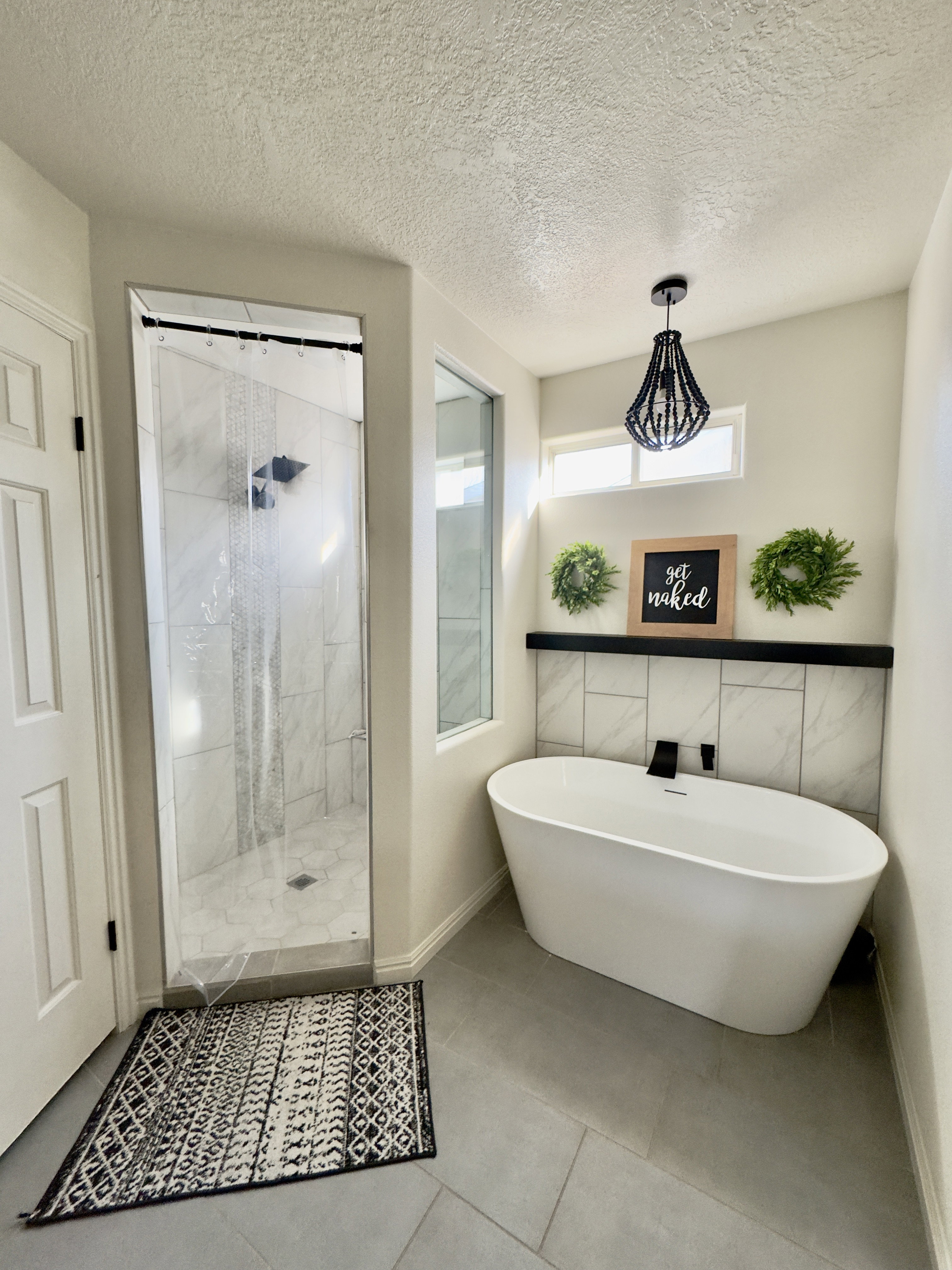 Bathroom with a shower stall, a freestanding tub, a textured ceiling, and tile patterned flooring