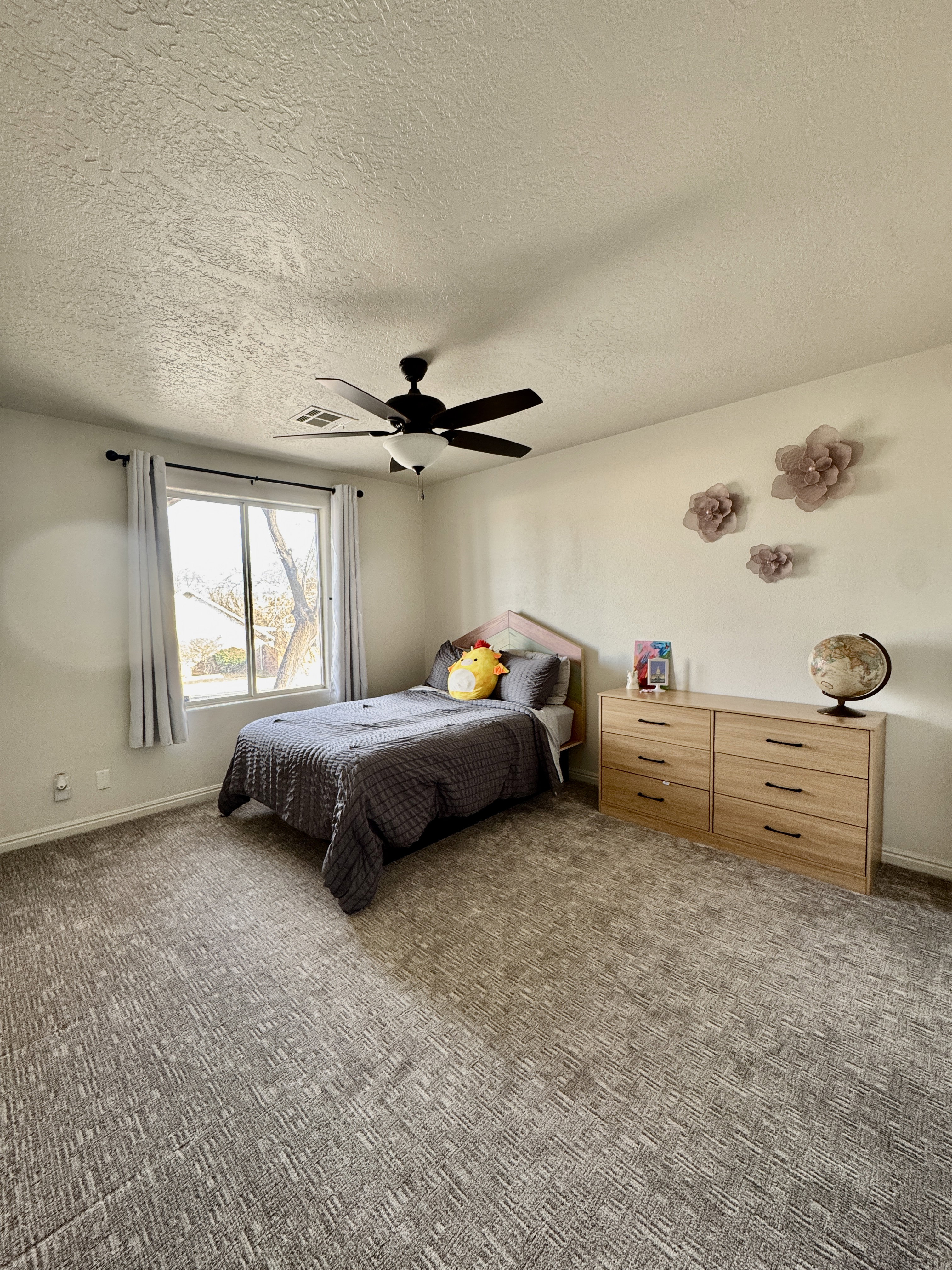 Carpeted bedroom with a textured ceiling and ceiling fan