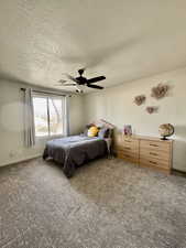 Carpeted bedroom with a textured ceiling and ceiling fan
