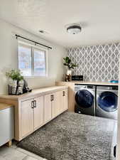 Laundry area with washer and clothes dryer, cabinet space, and a textured ceiling