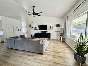 Living area with a ceiling fan and light wood-style flooring