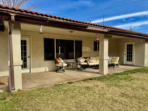 Rear view of house with a patio, a yard, and stucco siding