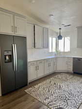 Kitchen with stainless steel appliances, dark wood finished floors, backsplash, and light stone countertops